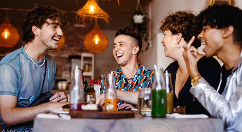 Cheers! Group of gender queer friends socialise with alcohol on the table